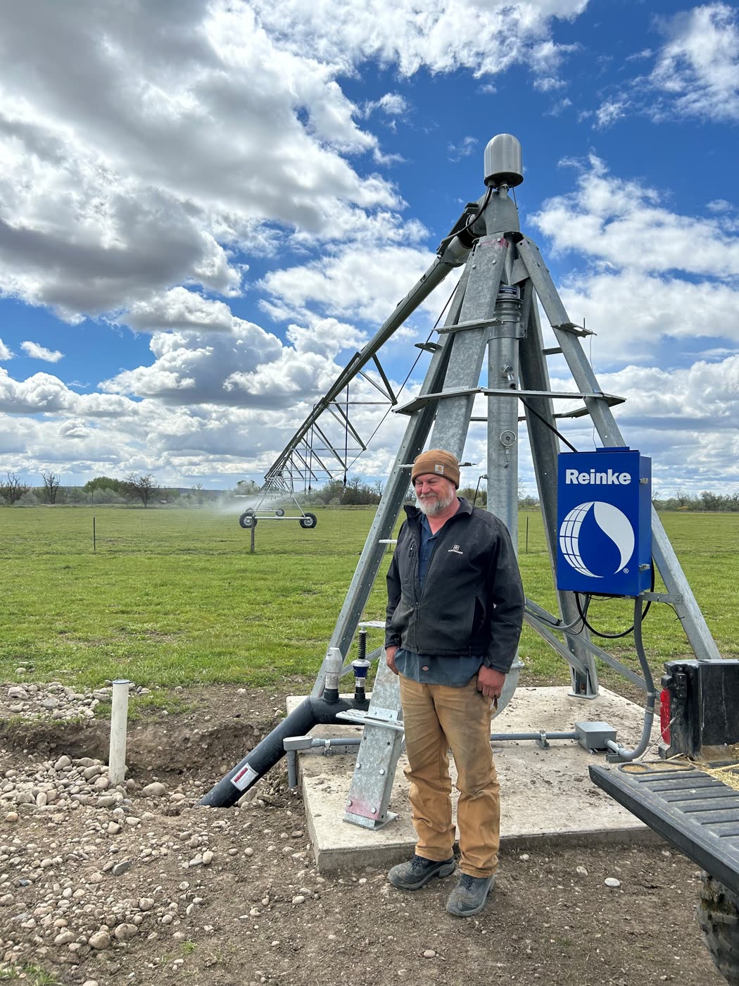 A Gem County landowner standing at a Reinke center-pivot pump station in a green field